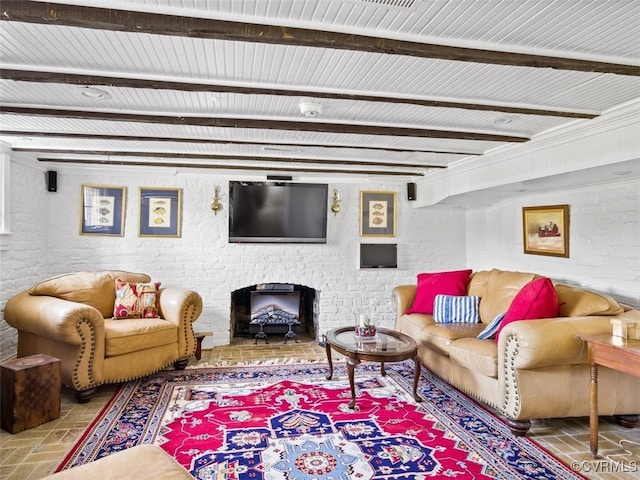 living room featuring brick floor, a brick fireplace, beamed ceiling, and brick wall