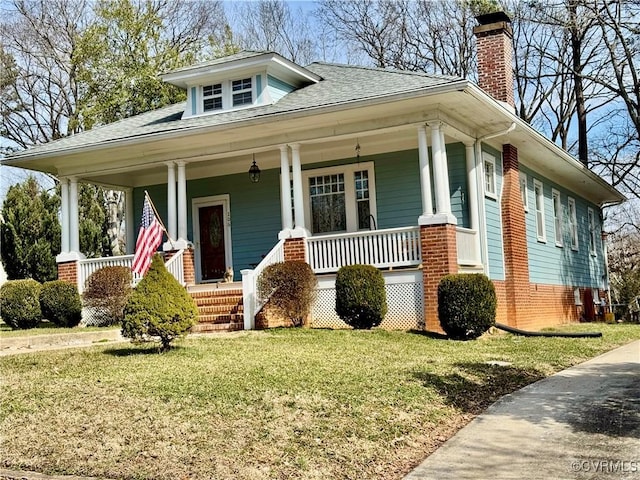 bungalow-style home with a porch, a shingled roof, a chimney, and a front lawn