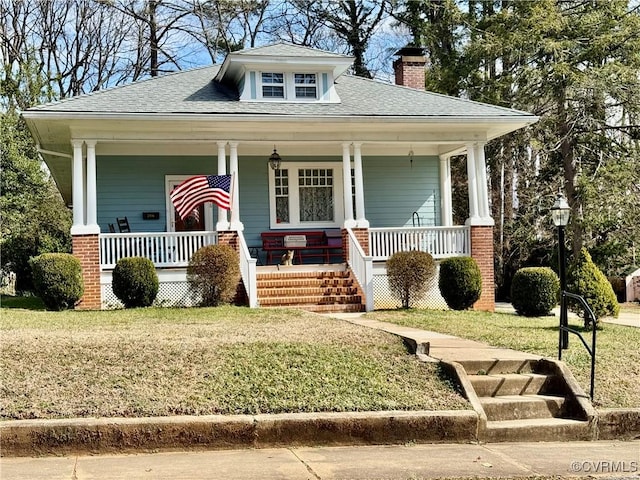 bungalow-style house featuring a porch, a chimney, a front yard, and a shingled roof