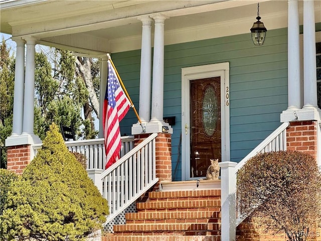 view of exterior entry featuring covered porch and brick siding