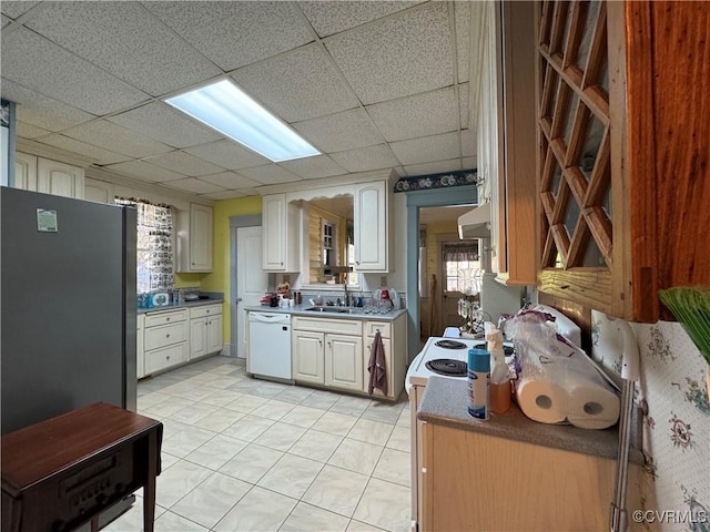 kitchen with white appliances, a drop ceiling, under cabinet range hood, a sink, and light tile patterned flooring