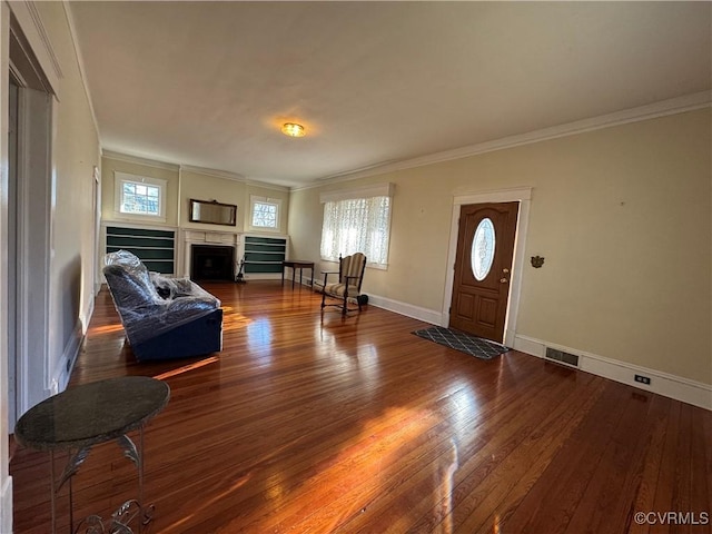 foyer entrance with hardwood / wood-style flooring, a fireplace, visible vents, baseboards, and ornamental molding