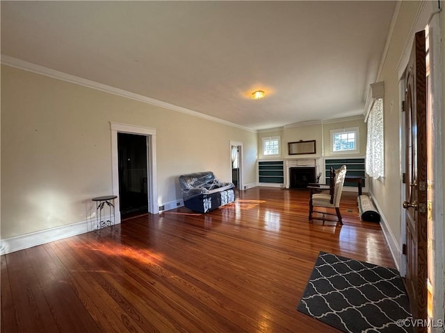 living area featuring wood-type flooring, baseboards, and crown molding