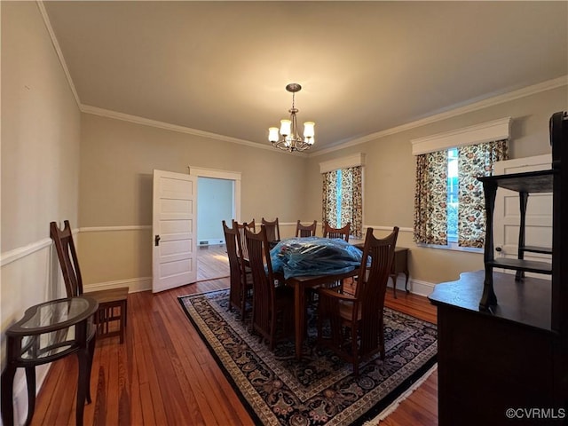 dining space featuring ornamental molding, wood-type flooring, baseboards, and an inviting chandelier