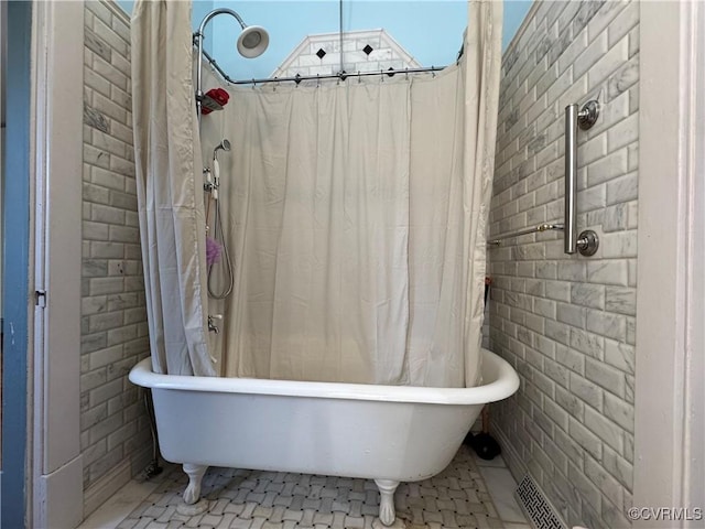 full bathroom featuring a freestanding bath, brick wall, and a shower with shower curtain