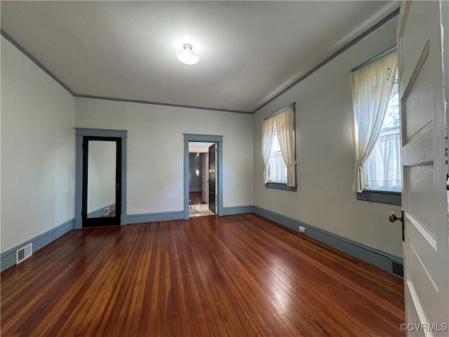 unfurnished room with visible vents, hardwood / wood-style flooring, and baseboards