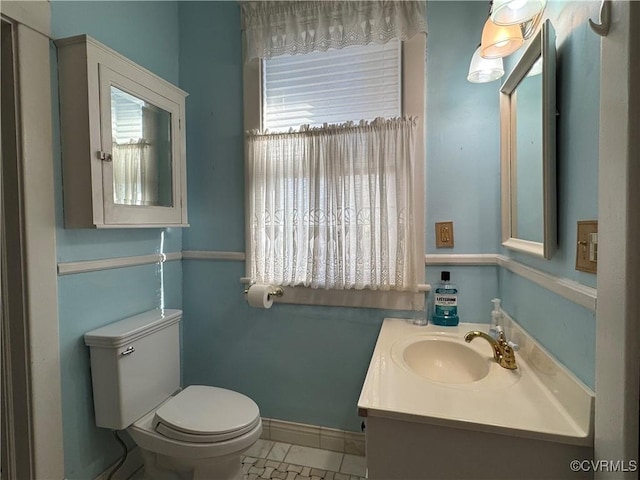 bathroom with toilet, baseboards, and vanity