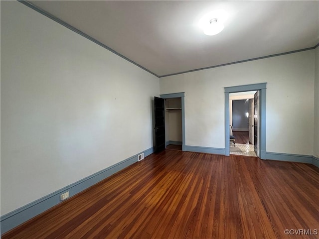 unfurnished bedroom with a closet, visible vents, baseboards, and wood finished floors