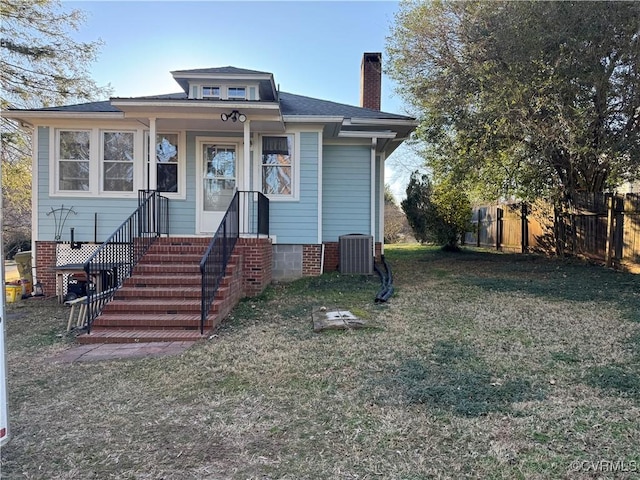 bungalow with a front yard, fence, a chimney, and central air condition unit