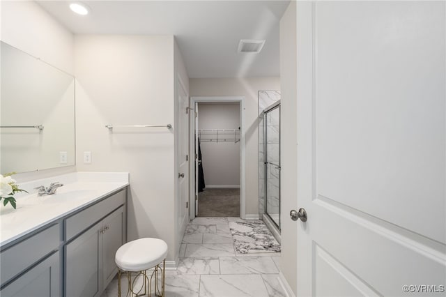 full bathroom with visible vents, vanity, marble finish floor, a shower stall, and a walk in closet