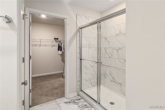 full bathroom with a stall shower, baseboards, a spacious closet, and marble finish floor