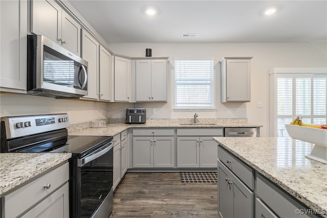 kitchen featuring appliances with stainless steel finishes, gray cabinets, a sink, and recessed lighting