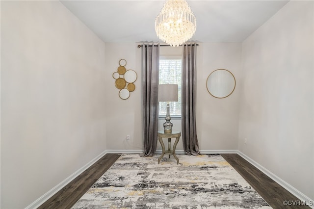 unfurnished room with dark wood-style floors, an inviting chandelier, and baseboards