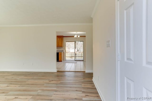 empty room featuring crown molding, light wood-style flooring, baseboards, and an inviting chandelier