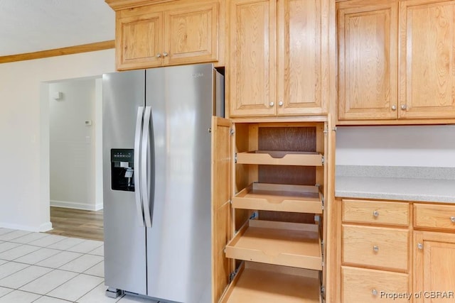 kitchen featuring light tile patterned floors, stainless steel fridge with ice dispenser, light countertops, light brown cabinetry, and baseboards