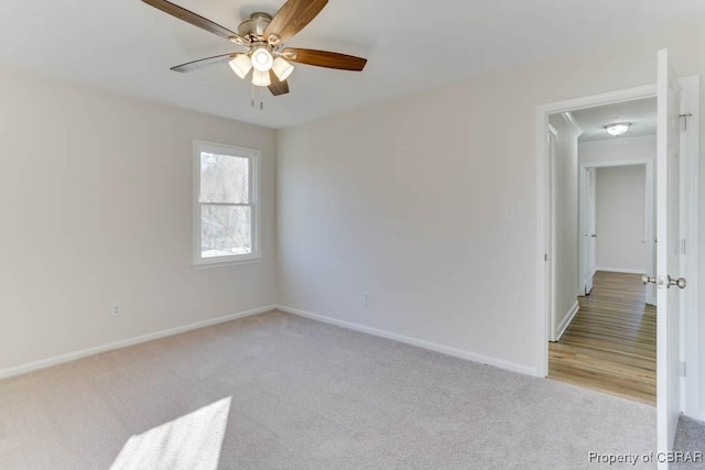 spare room with a ceiling fan, light colored carpet, and baseboards