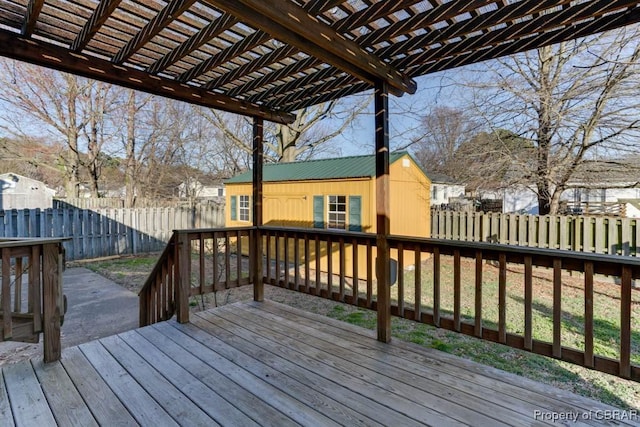 wooden deck with a fenced backyard, a pergola, and an outbuilding