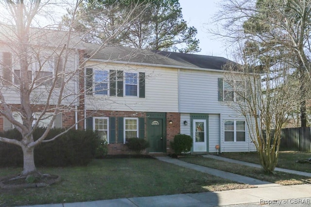 townhome / multi-family property with brick siding, fence, and a front lawn