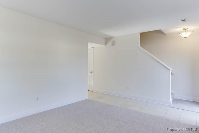 spare room featuring light carpet, light tile patterned floors, visible vents, and baseboards