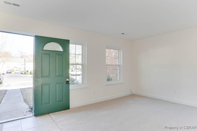 entrance foyer featuring light colored carpet, visible vents, and baseboards