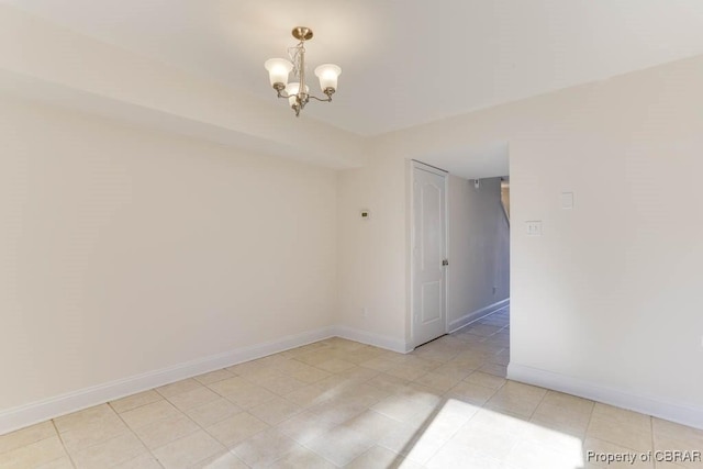 unfurnished room featuring a chandelier and baseboards