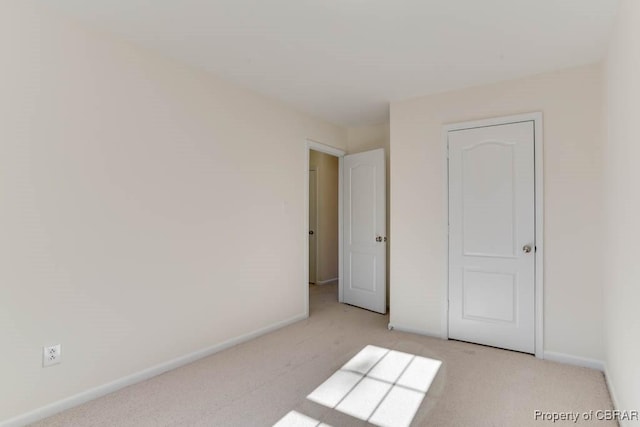 unfurnished bedroom featuring baseboards and light colored carpet