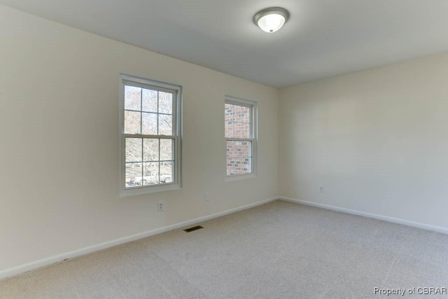 spare room with light carpet, visible vents, and baseboards