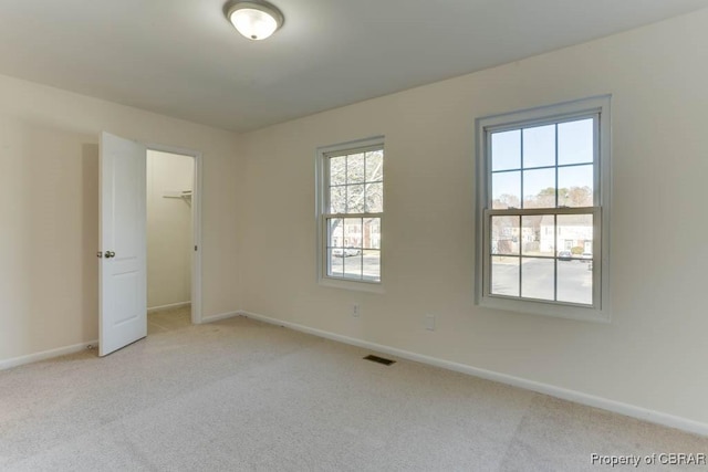 spare room featuring baseboards, visible vents, and light colored carpet