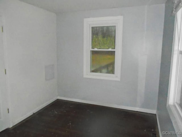 spare room featuring baseboards and wood finished floors