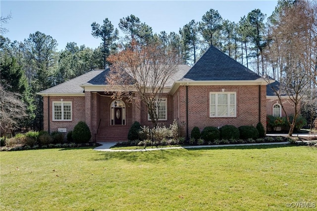 ranch-style home with a shingled roof, a front yard, and brick siding