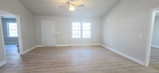 interior space with ceiling fan, vaulted ceiling, baseboards, and wood finished floors