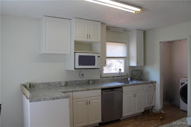 kitchen featuring white microwave, washer / dryer, stainless steel dishwasher, white cabinetry, and a sink