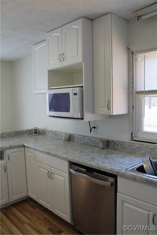 kitchen featuring white microwave, white cabinets, dishwasher, and a textured ceiling