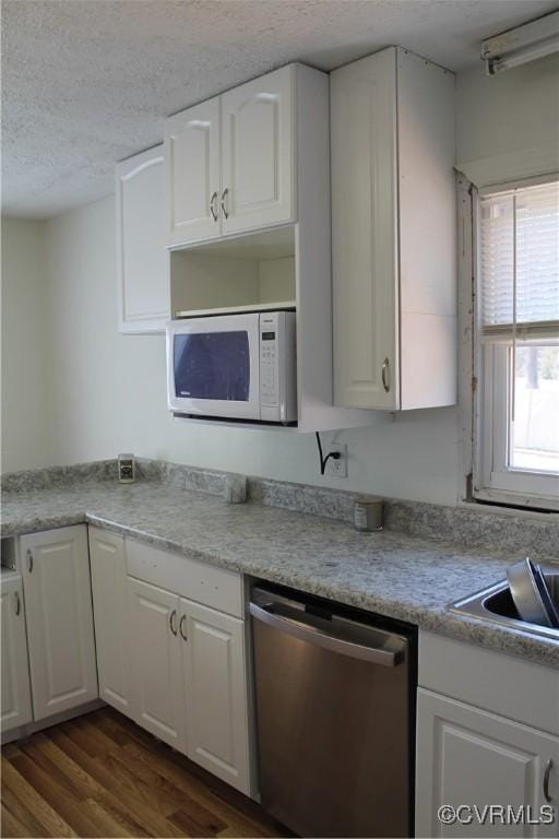 kitchen featuring a textured ceiling, white microwave, white cabinets, and dishwasher