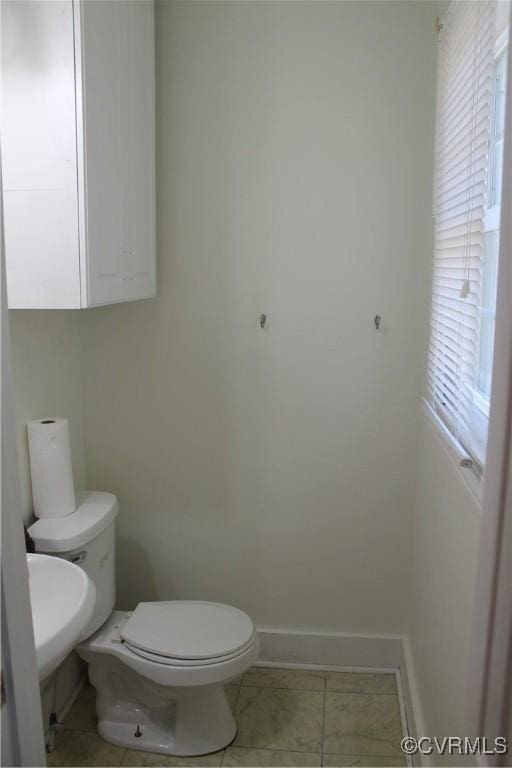 half bath with tile patterned flooring, toilet, and baseboards