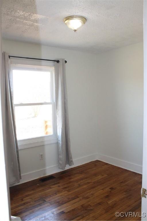 empty room featuring visible vents, baseboards, a textured ceiling, and hardwood / wood-style flooring