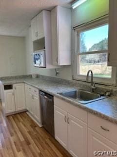 kitchen with white cabinets, a sink, light countertops, and dishwasher
