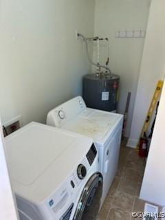 clothes washing area featuring water heater, separate washer and dryer, laundry area, and tile patterned flooring