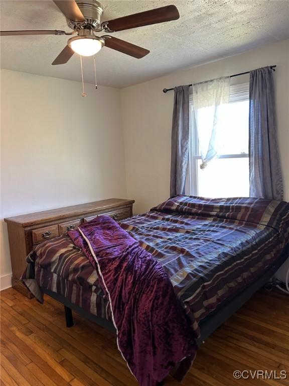 bedroom featuring a ceiling fan, hardwood / wood-style flooring, and a textured ceiling