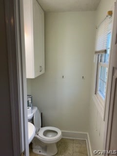 bathroom featuring toilet, tile patterned floors, and baseboards