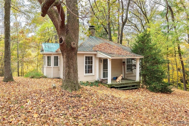 exterior space with metal roof, a porch, and a chimney