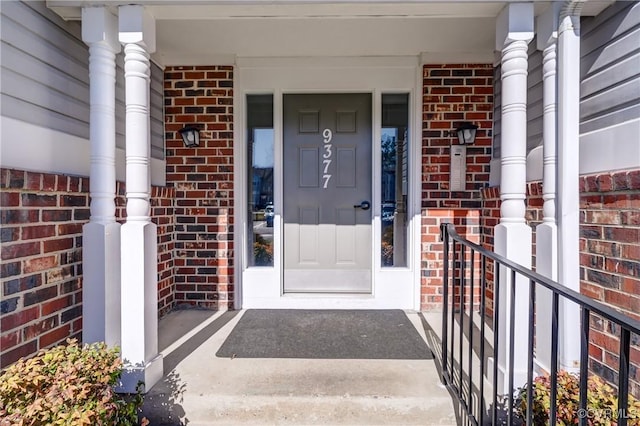 entrance to property with covered porch and brick siding