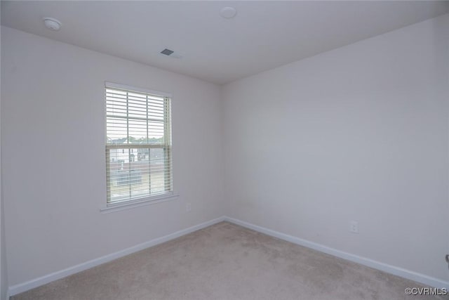 empty room with baseboards, visible vents, and light colored carpet