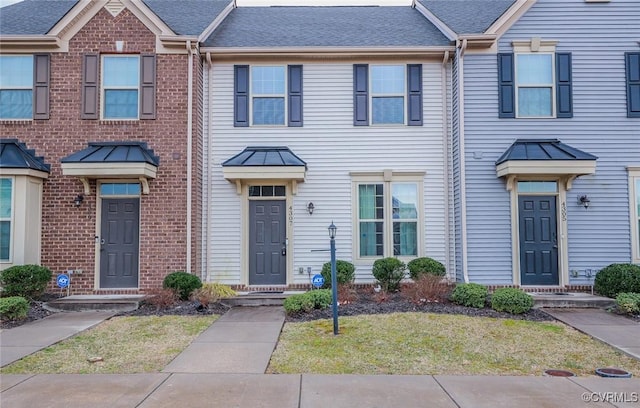 townhome / multi-family property with a shingled roof and brick siding