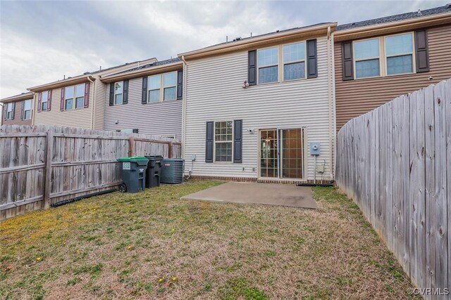 rear view of house with a patio area, a fenced backyard, central AC unit, and a lawn