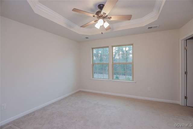 spare room featuring baseboards, a raised ceiling, a ceiling fan, light colored carpet, and crown molding