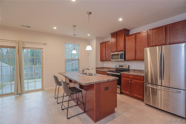 kitchen with decorative light fixtures, recessed lighting, appliances with stainless steel finishes, a sink, and an island with sink