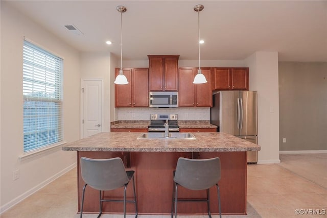 kitchen featuring stainless steel appliances, tasteful backsplash, visible vents, a kitchen island with sink, and a sink