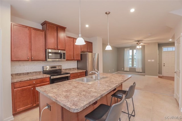 kitchen featuring a sink, light countertops, appliances with stainless steel finishes, tasteful backsplash, and a center island with sink