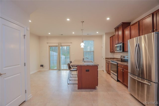 kitchen with an island with sink, appliances with stainless steel finishes, decorative light fixtures, a sink, and recessed lighting